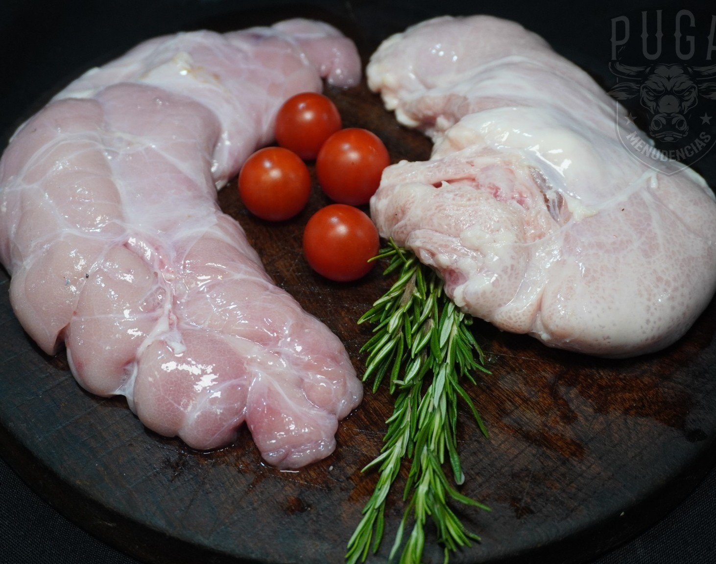 Menudencias frescas de Puga sobre tabla de madera con romero y tomates